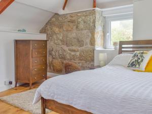 a bedroom with a bed and a stone wall at First Floor The Hayloft in Porthcurno