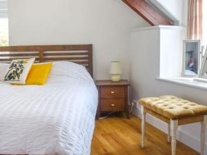 a bedroom with a bed and a chair and a window at First Floor The Hayloft in Porthcurno