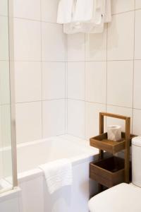 a white bathroom with a tub and a toilet at Les Douvres Hotel in St. Martin Guernsey