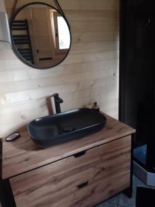 ein Bad mit einem schwarzen Waschbecken und einem Spiegel in der Unterkunft Domki letniskowe Balia sauna Leśny Czar in Raków