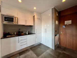 a kitchen with white cabinets and a sink and a microwave at Prime Loft ANDORRA HUT2-06207 in Pas de la Casa