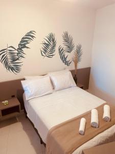 um quarto com uma cama com lençóis brancos e folhas de palmeira na parede em Pousada Hoffmann em Florianópolis