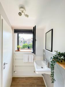 biała łazienka z umywalką i oknem w obiekcie SEEBADHOF Berlin-Rangsdorf w mieście Rangsdorf