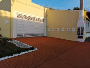 a white garage door on a building with a brick driveway at Apartamento Aconchegante de luxo da Elena in São Carlos