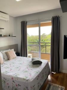 um quarto com uma cama e uma grande janela em Flat Studio Granja Viana Completo 411 em Cotia