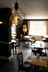 a restaurant with tables and chairs and a chandelier at The Plough Itchen Abbas in Winchester