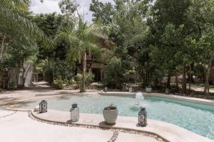 a swimming pool with a fountain in a yard at Cachito de Cielo Luxury Jungle Lodge in Tulum