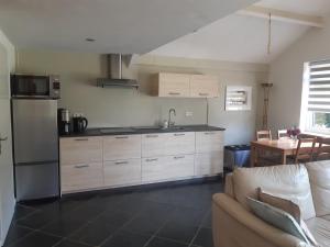 a kitchen with white cabinets and a couch and a table at De Steegberg Holiday Home in Sevenum