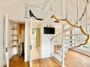 a white staircase in a house with a tv at The Hazeling Hideaway in Stroud