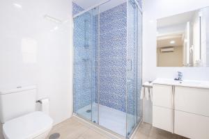a bathroom with a glass shower with a toilet and a sink at Apartamentos La Rosita Old Town in Benidorm