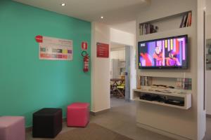 uma sala de estar com uma televisão de ecrã plano na parede em Concept Design Hostel & Suites em Foz do Iguaçu