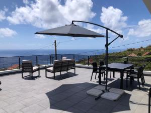 Estreito da Calheta的住宿－Calheta Ocean View Family Apartment，庭院配有桌椅和遮阳伞。