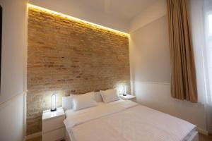 Ce lit se trouve dans une chambre dotée d'un mur en briques. dans l'établissement Carol Residence, à Timişoara