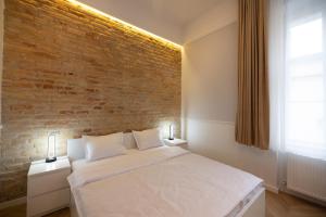 a bedroom with a white bed with a brick wall at Carol Residence in Timişoara
