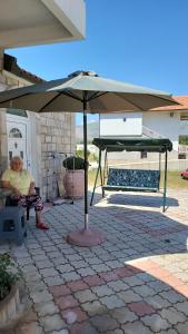 a woman sitting under an umbrella on a patio at Apartmani Lux in Trebinje