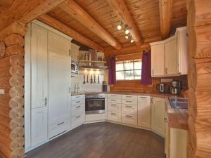 cocina con armarios blancos y techo de madera en Comfortable holiday home with hot tub, en Teunz