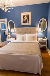 a bedroom with blue walls and a bed with two mirrors at Manoir Becancourt Hotel in Bécancour