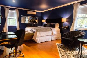 a bedroom with a bed and a desk and chairs at Manoir Becancourt Hotel in Bécancour