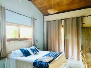 Un dormitorio con una cama con almohadas azules y una ventana en Carpe Diem Suítes Taipu de Fora, en Maraú