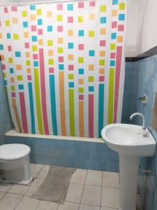 uma casa de banho com uma cortina de chuveiro, um WC e um lavatório. em Hostel Cachoeira em Porto Alegre