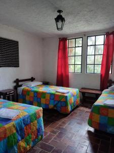 a bedroom with two beds and two windows at Posada Montaña del Quetzal in Cobán