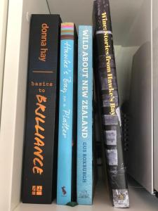 a group of books sitting on a shelf at River View Cottage in Kahuranaki