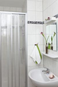 baño blanco con ducha y lavamanos en Hotel Arche, en Berlín