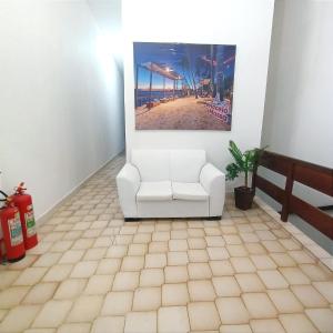 una sala de estar con una silla blanca y una foto de la playa en Pousada Sol e Mar de Pajuçara, en Maceió