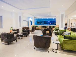 a lobby with couches and chairs and a tv at BON Hotel Garden City Port Harcourt in Umudara