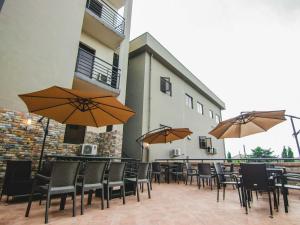 un patio con mesas, sillas y sombrillas en BON Hotel Garden City Port Harcourt, en Umudara