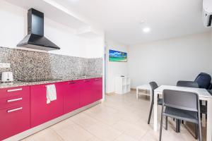 a kitchen with red cabinets and a table with chairs at Apartamentos La Rosita Old Town in Benidorm