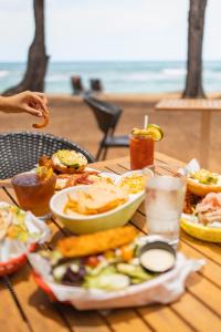 a table topped with plates of food and drinks at Kauai Shores Hotel in Kapaa