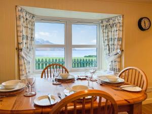 un tavolo da pranzo con sedie e una grande finestra di Grieves Cottage ad Arnisdale