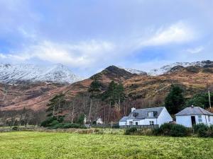 a house in a field with mountains in the background at Grieves Cottage in Arnisdale