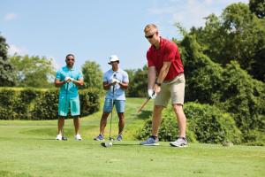 three men playing golf on a golf course at Sawmill Creek by Cedar Point Resorts in Sandusky