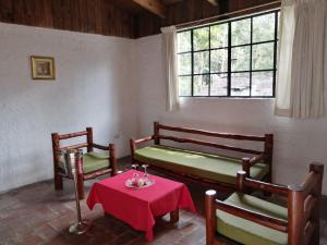 a room with two benches and a table and a window at Posada Montaña del Quetzal in Cobán