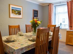 a dining room table with a vase of flowers on it at Woodville in Porthmadog