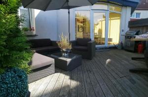 a patio with a couch and an umbrella at Schöne Wohnung mit abgeschlossenem Grundstück zentral und ruhig in Greifswald