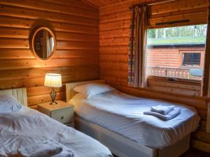 two beds in a log cabin with a window at Cosy Lodge - Uk37418 in Legbourne