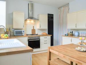 a kitchen with white cabinets and a wooden table at Ty Kinik in Llangollen