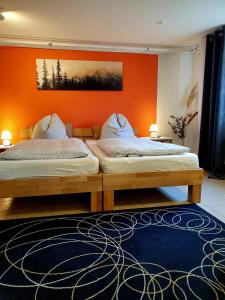 two beds in a bedroom with an orange wall at Apartment Souterrain Bühl Vimbuch Familie Bork in Bühl