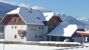 a house in the snow with mountains in the background at Gästehaus Wallner in Presseggen