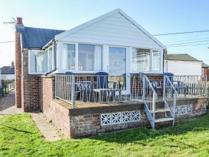 a house with a deck with chairs and a table at Sea Scape in Bacton