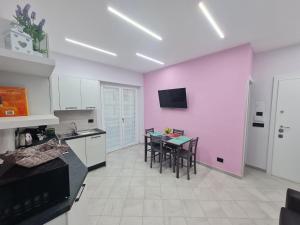 a kitchen with a table and chairs and a pink wall at Il Piccolo Sogno di Roma in Rome