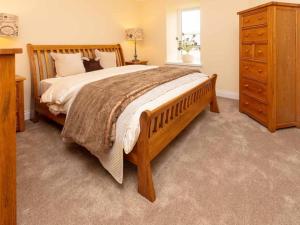 a bedroom with a large wooden bed and a dresser at The Cottage At Briarlea in Larkhall