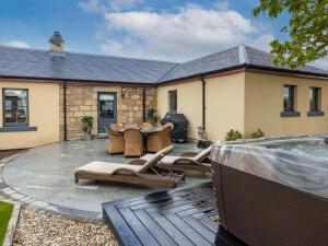 um pátio com uma mesa e cadeiras e uma piscina em The Cottage At Briarlea em Larkhall