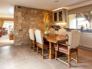 uma sala de jantar com uma mesa de madeira e cadeiras em The Cottage At Briarlea em Larkhall