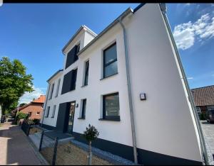 a white building with black windows on a street at Ferienwohnung - Melina - in Winsen