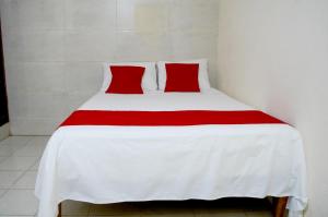 a white bed with two red pillows on it at Hotel Rosa del Alba, Barrio Mágico Centro Histórico de Chetumal in Chetumal