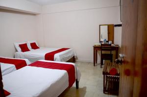 a room with two beds and a desk with a mirror at Hotel Rosa del Alba in Chetumal